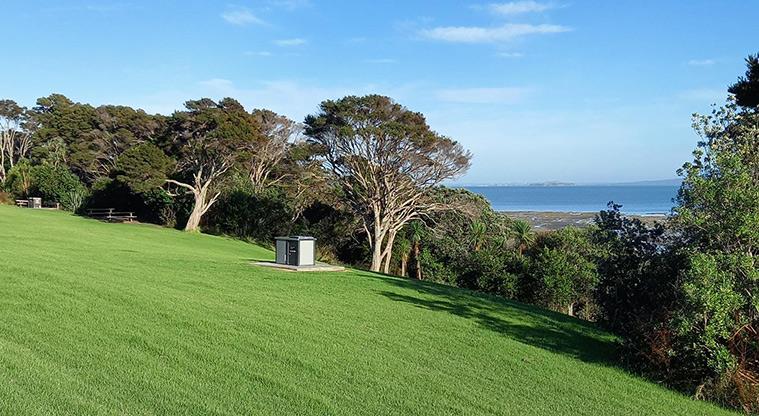 Ōmana Regional Park - Bookable site one with open space, and the barbecue and trees in the background.
