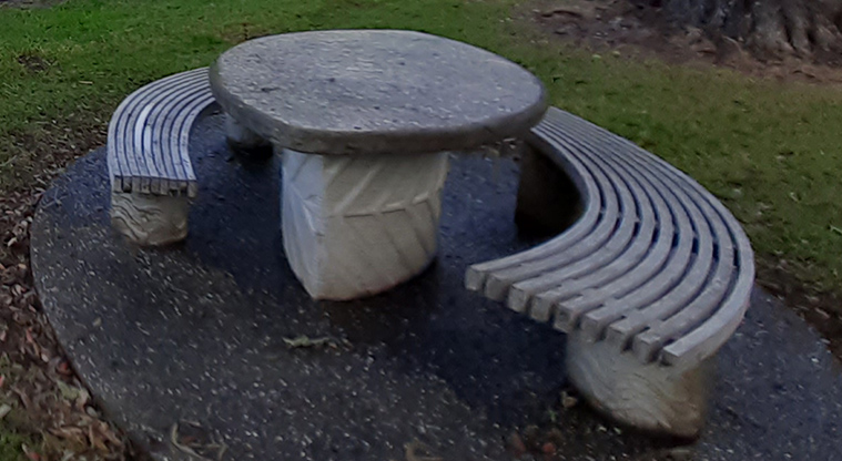 Cockle Bay Reserve - Round concrete picnic table with curved wooden seats on a concrete base.