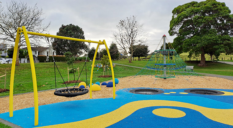 Crossfield Reserve - Basket swing, in-ground trampolines and net climbing frame with open space and trees in the background.