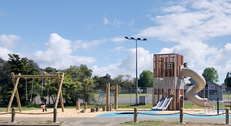 Edith Hopper Park - Playground with a set of two swings, climbing nets and stumps, and a tall tower with slides and climbing equipment.
