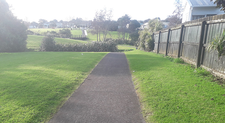 Maybury Reserve - Section of the path going through the reserve with trees, a bridge and open space in the background.