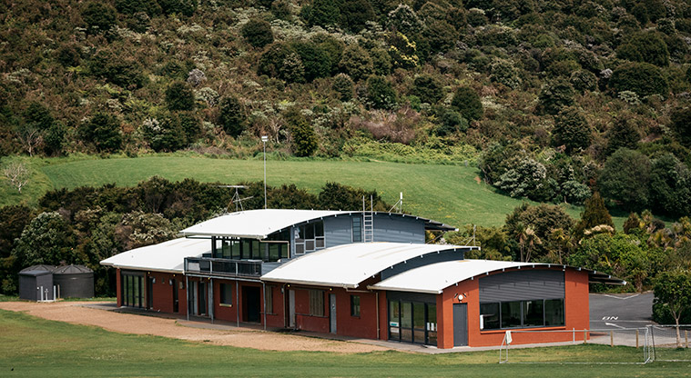 Onetangi Sports Park - The sports pavilion with grassed spaces and bush in the background.