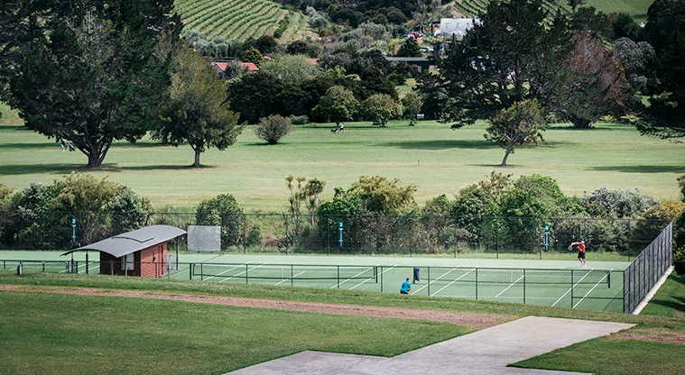 Onetangi Sports Park - The fenced tennis courts with a section of the golf course in the background.