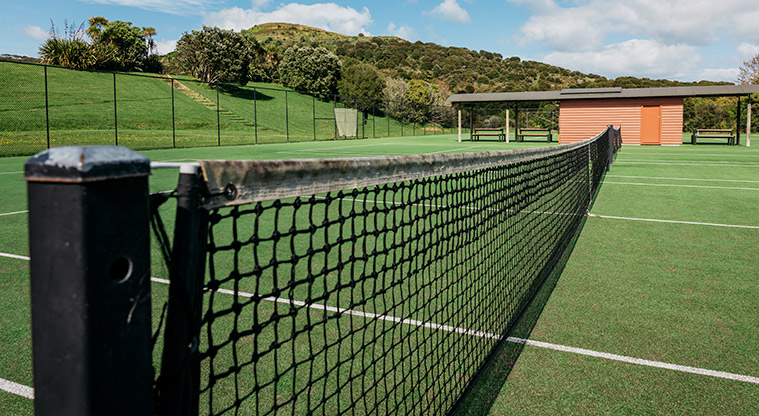 Onetangi Sports Park - Part pf the tennis court and net with the seating and shelter in the background.