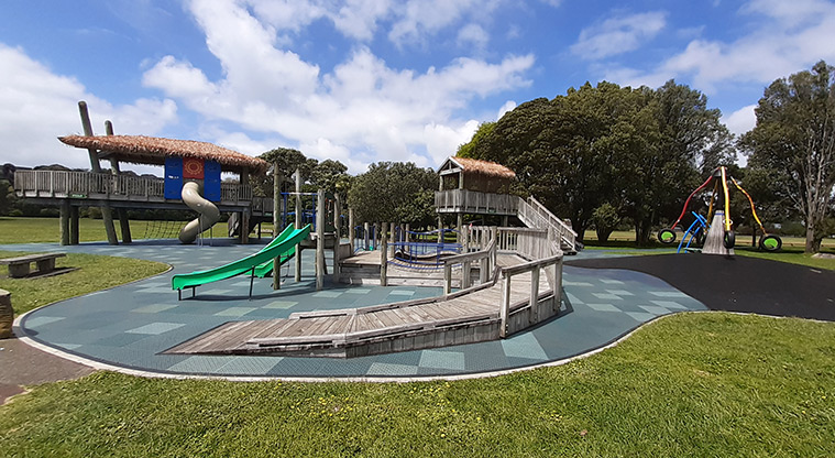 Ōrākei Domain - Playground with play huts, slides, and a rocktopus, with trees in the background.
