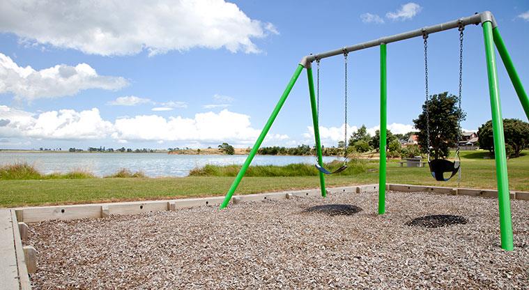 Pāpākiri / Saint Annes Foreshore - Swings with harbour views in the background.