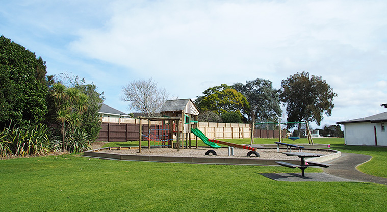 Te Atatu Peninsula Park - Playground with a cubby house, double slide, climbing nets, seesaw and round spinner.